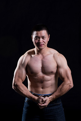 身材健美的肌肉男在黑暗的健身房摆姿势