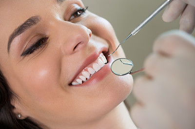 一位年轻女子正露出牙齿让牙医检查