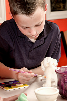 8岁白人男孩画陶器