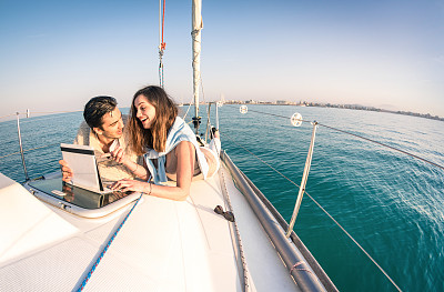 年轻夫妇在帆船上玩平板电脑相爱