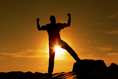 剪影的赢家年轻人张开双臂