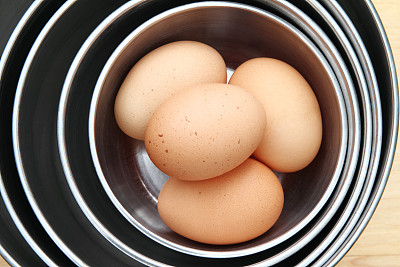 在一堆搅拌碗中放入棕色的鸡蛋