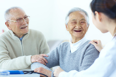 一对年长的亚洲夫妇在和他们的护士聊天
