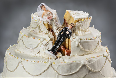 新娘和新郎的小雕像倒在了毁了的婚礼蛋糕上