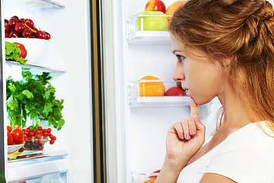 快乐的女人又打开冰箱装着水果、蔬菜