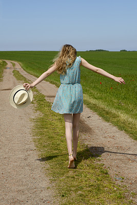少女戴着太阳帽走在土路上