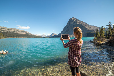 女人从岛上的岩石上拍摄山湖
