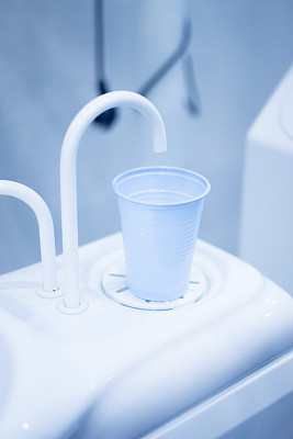 牙科医生在牙科诊所用清水冲洗杯子