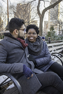 相爱的多民族情侣坐在公园长椅上
