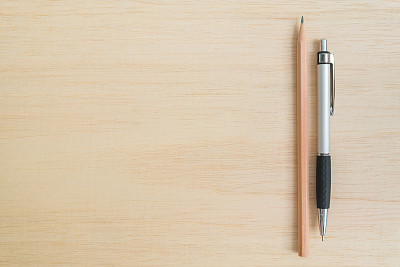 棕色的铅笔和钢笔在木制的背景上
