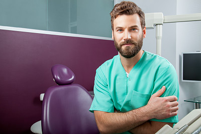 男医生在牙科诊所胡子在绿色服装
