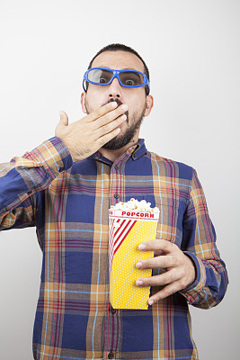 年轻人戴着3d眼镜吃着爆米花看电影