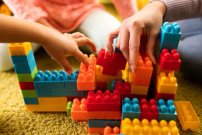 儿童和妇女玩塑料积木的特写。