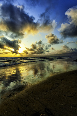 日出时热带海滩上戏剧性的天空反射