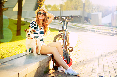 夏日城市里微笑的嬉皮士女孩和她的狗
