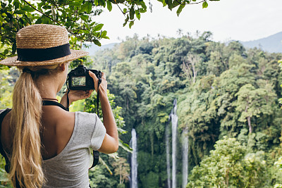 女游客在森林里拍摄瀑布