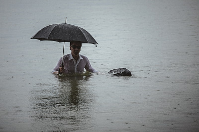 帅气的男人穿着白衬衫，在下雨的时候撑着伞