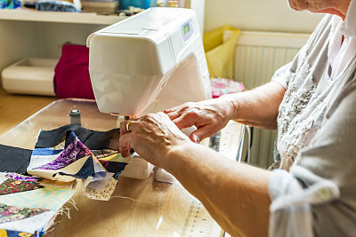 一位老年妇女的手把缝制被子作为一种爱好