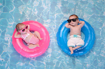双胞胎男孩和女孩漂浮在游泳环上