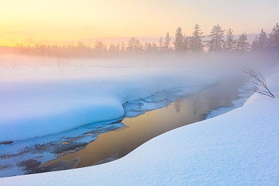 色彩缤纷的冬季日落在森林和河流与美丽的薄雾