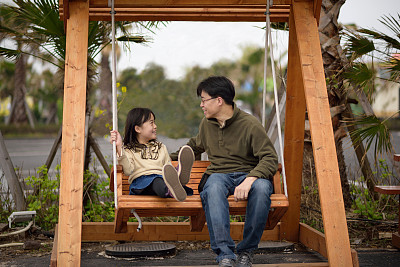 亚洲孩子和父亲坐在秋千上