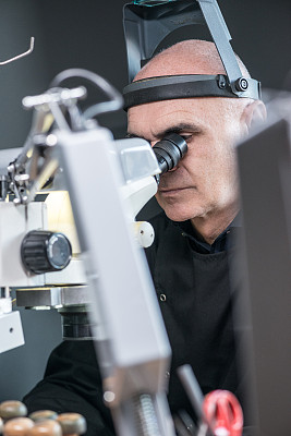 专业的宝石镶嵌珠宝工艺实验室:用显微镜工作的人