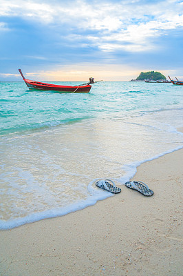 人字拖(凉鞋)在沙滩上。暑假的概念