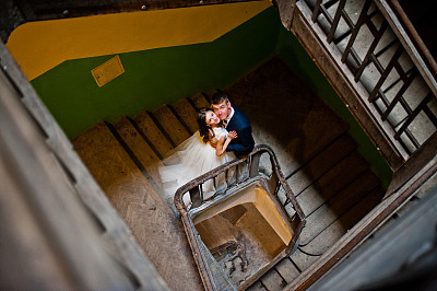 一对新婚夫妇站在一所老房子入口处的木楼梯上
