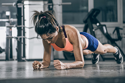 运动。肌肉发达的女人在一个平板姿势。