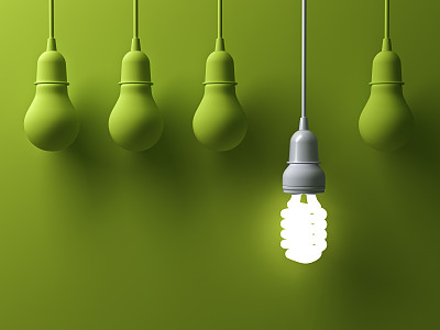 一个悬挂的节能灯泡发光不同，从未点亮的白炽灯泡在绿色背景与阴影，领导和不同的创意概念。三维渲染