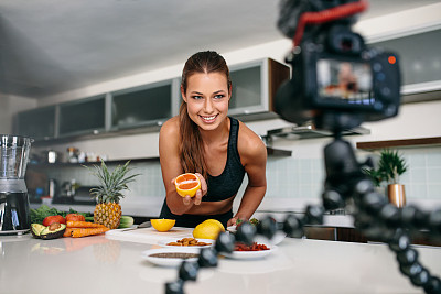 年轻女性博客录制内容的视频博客在厨房。