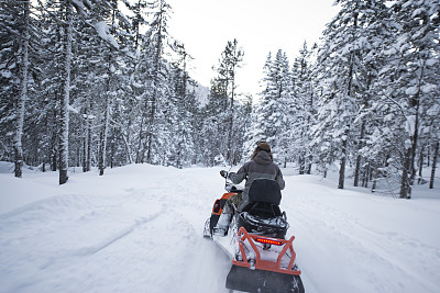 在冰霜森林中驾驶雪地摩托旅行的司机。