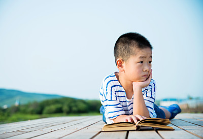 一个亚洲小男孩在大自然中读书