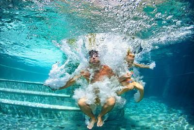 快乐家庭在游泳池潜水与乐趣