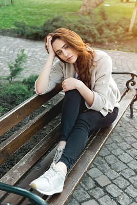 悲伤的女孩坐在长椅上