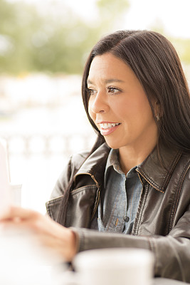 一名妇女在户外咖啡馆使用平板电脑。
