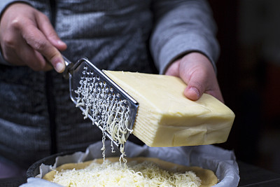 刮着马苏里拉奶酪，覆盖在披萨上