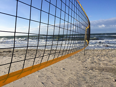 沙滩排球网特写。蔚蓝多云的天空和海滩上黄色的沙子