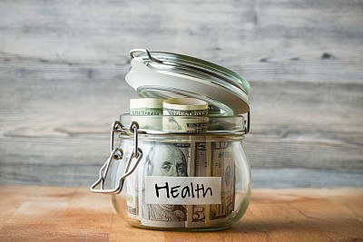 在木制背景上孤立的玻璃罐中的美元。为健康存钱。