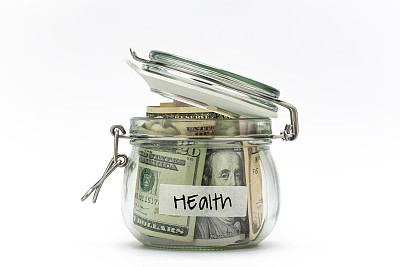 在白色背景上孤立的玻璃罐中的美元。为健康存钱。
