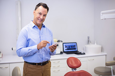 微笑的牙医使用手机的肖像