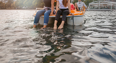 脚踏船上的两个年轻女人，脚浸在水里