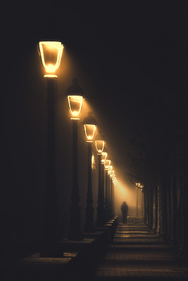 走在被路灯照亮的黑暗街道上的人