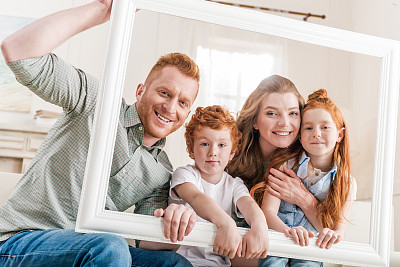 幸福的红发家庭透过白色的框架一起看，大的家庭肖像概念