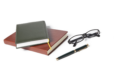 钢笔、笔记本和眼镜在白色的背景上