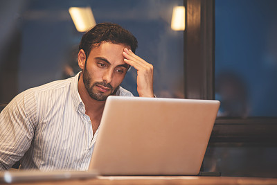 压力大的商人用笔记本电脑思考，工作时头痛。