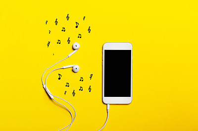 黄色背景上的耳机智能手机的特写。(前视图)。听音乐。