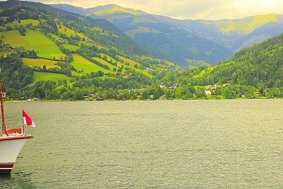 船漂浮在美丽的泽勒湖和奥地利国旗-泽尔am See和山脉景观，Tirol Salzburger土地，奥地利