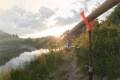 钓竿竖立在抛入水中用于钓鱼的支撑物上的钓竿
