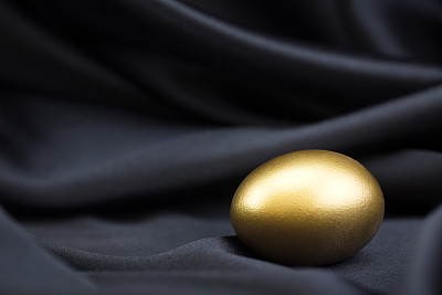 黑色缎子背景上的金蛋体现了聪明的成功